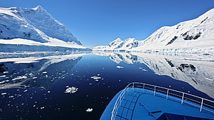 white cruiser ship on body of water between mountain covered with snow during daytime