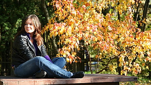 woman in black leather jacket sitting on wooden platform HD wallpaper