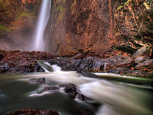 body of water beside of brown rock formation HD wallpaper