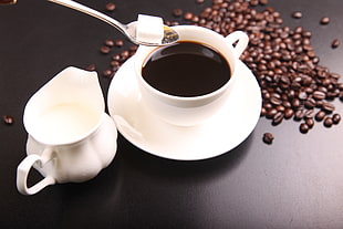black liquid in white ceramic teacup beside coffee beans HD wallpaper