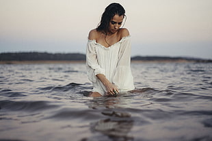 woman in white long sleeve off-shoulder shirt standing on body of water during daytime HD wallpaper