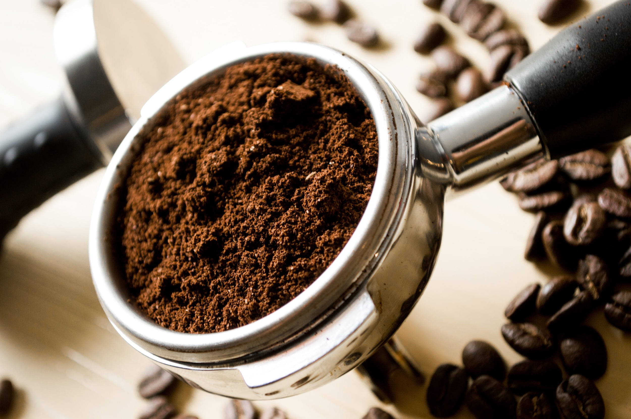 depth of field photography of ground coffee on espresso machine over roasted coffee beans