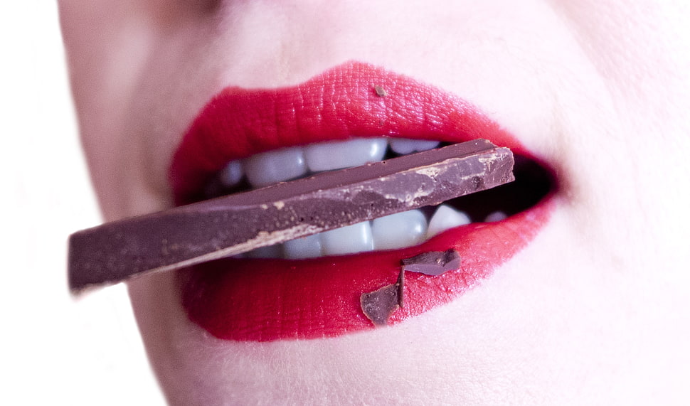 woman in red lipstick biting chocolate HD wallpaper