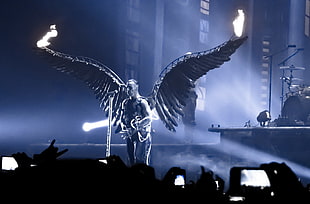 man with black wings holding guitar