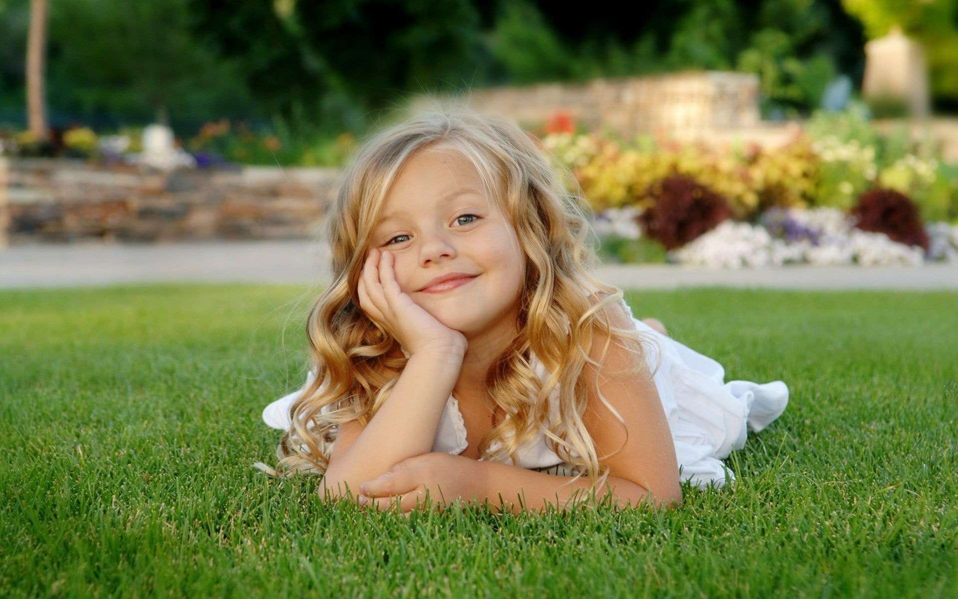 Blonde Haired Girl In White Dress Laying Down On Green Grass With Head On Right Hand Smiling Hd