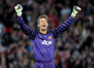 goal keeper in purple jersey raising his hands