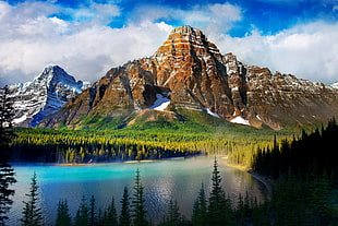 large body of water near mountain under cloudy sky during daytime