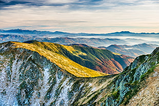 green grass on mountains during cloudy daytime