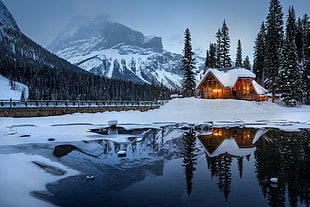 house near lake covered with snow near mountain