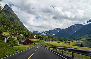 black top road across rocky mountains under white sky during daytime, sykkylven