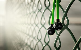 green earphones hanged on cyclone fence HD wallpaper