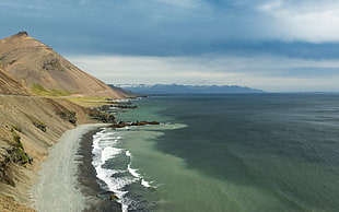 seashore near road and mountain during daytime