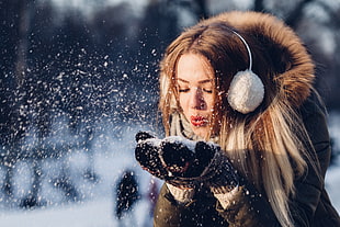 woman wearing coat and earmuffs blowing snow HD wallpaper