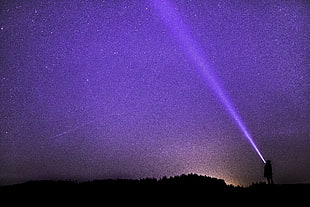 person with flashlight outside house looking at the stars