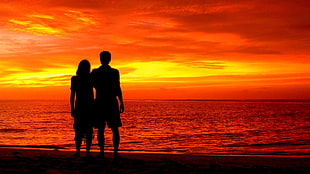 silhouette of a man and woman near shoreline