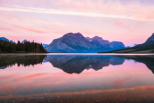 mountain and trees beside lake under white cloudy sky during daytime HD wallpaper