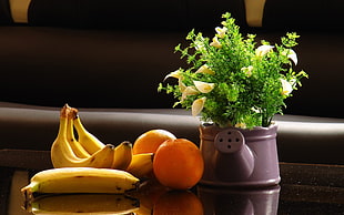 four bananas and two oranges next to watering can pot placed on brown wooden table HD wallpaper