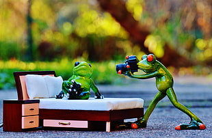 Frog plastic toy and bed with mattress miniature on gray floor