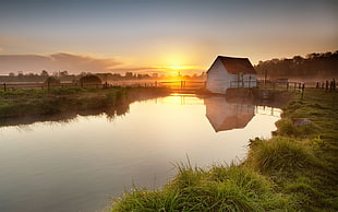 white and red barn near river at golden hour