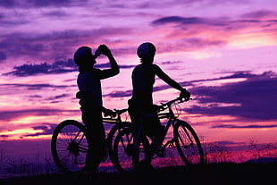 silhouette of two boy's riding mountain bike one drinking bottle during daytime HD wallpaper