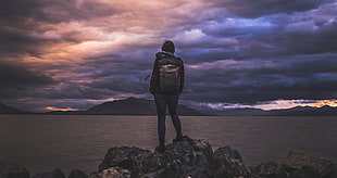 landscape photography of a person carrying brown backpack standing in mountain peak during golden hour HD wallpaper