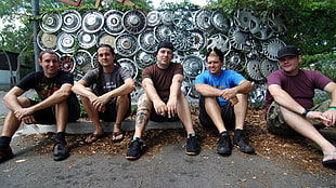 five men sitting on concrete path in front of wheel hub caps HD wallpaper
