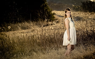 woman in yellow sleeveless midi dress standing beside brown grass