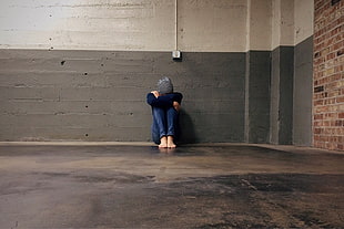 woman in long sleeve shirt sitting on black concrete floor