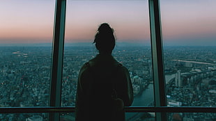 silhouette of woman facing glass wall overlooking city HD wallpaper