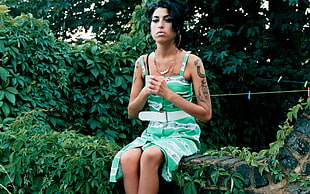 woman in green sleeveless dress sitting beside plants HD wallpaper