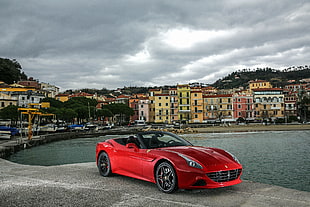 red Ferrari 458 Italia convertible parked on gray concrete pavement near body of water HD wallpaper