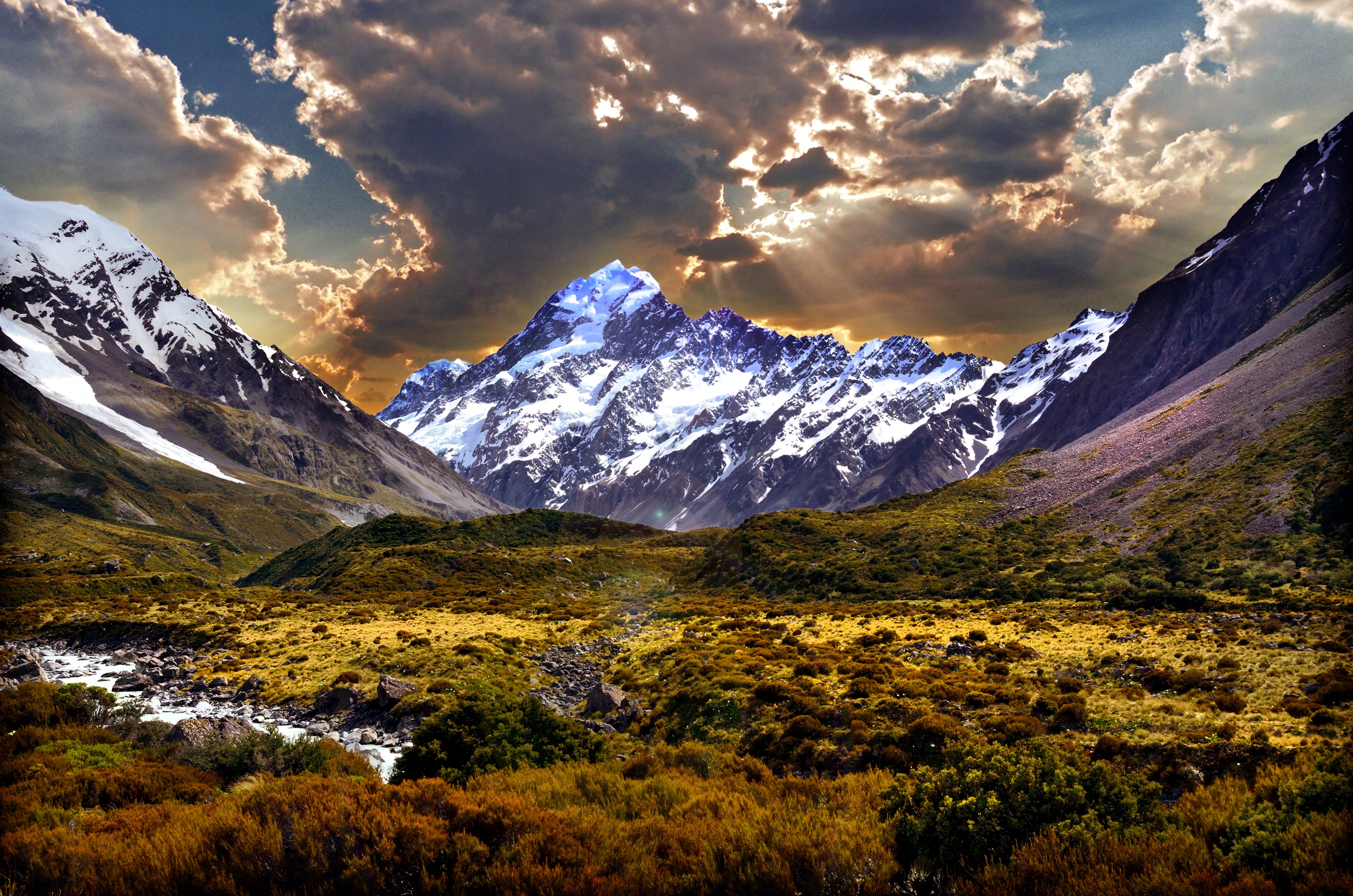 panaroma photo of mountain cover with snow near green field