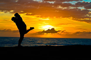 couple hugging near beach during golden hour HD wallpaper