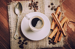 closeup photo of coffee in white mug beside spoon HD wallpaper