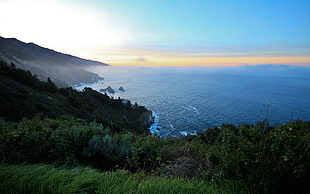 natures photography of sea surrounded by mountains