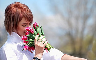 woman wearing white collared shirt snipping bouquet of pink tulips during daytime HD wallpaper