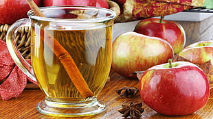 clear glass teacup beside red apple fruit