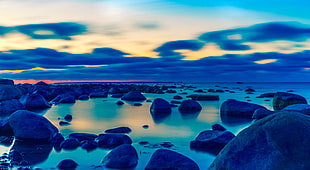 rock formation beside body of water during sun set