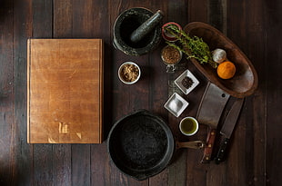 black mortar and pestle, brown wooden cutting board, black frying fan and two silver kitchen knives HD wallpaper