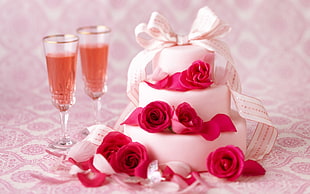 3-tier fondant cake covered by pink rose flowers beside champagne flute glasses filled with brown liquid HD wallpaper