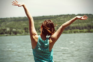 woman in tank top raising her hands in front of body of water during daytime HD wallpaper
