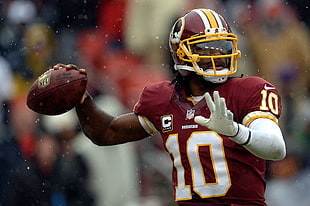 football player holding football during rainy day photo