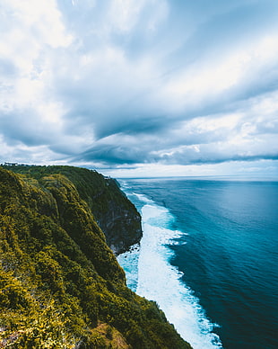 green mountain beside blue body of water