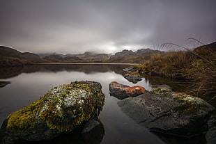 body of water near mountain under grey sky during daytime HD wallpaper
