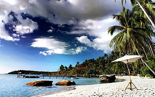 white umbrella on the seashore with rock formation view painting