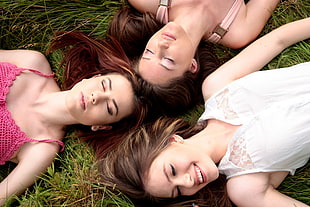 three women in camisoles lying on green grass HD wallpaper