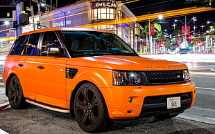 orange Range Rover parked on concrete road