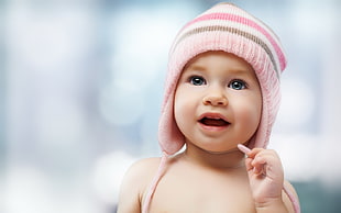 baby wearing pink chullo hat on blurry background HD wallpaper