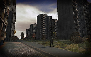 person walking near concrete high-rise buildings