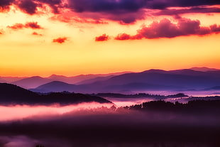 silhouette mountains under brown clouds